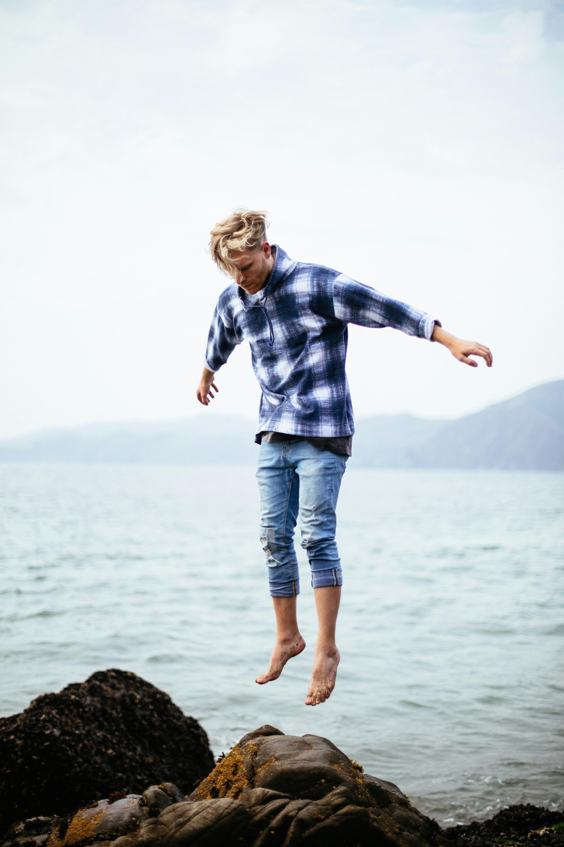 a man jumping off a rock in the water