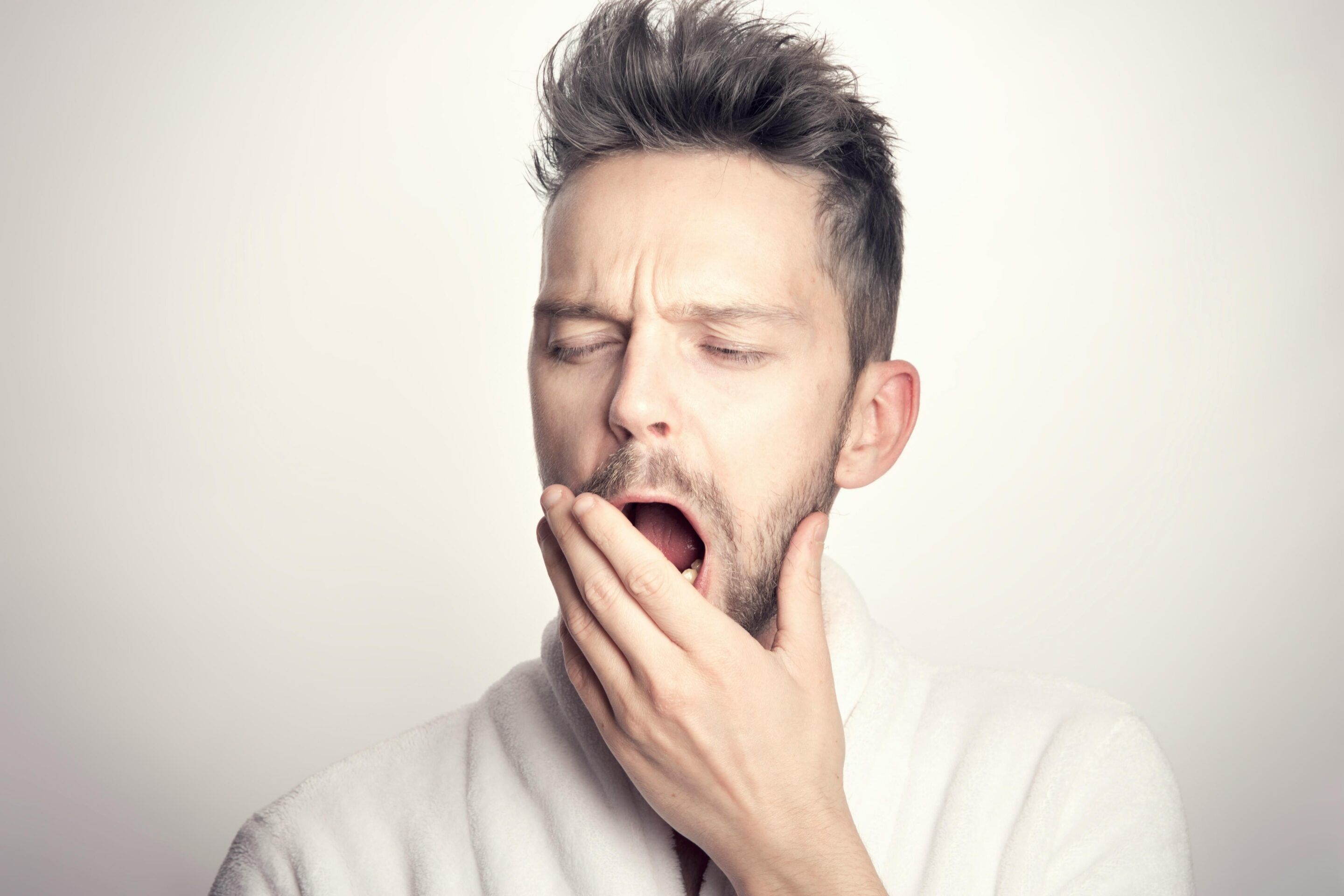 a man yawning with his hand to his mouth